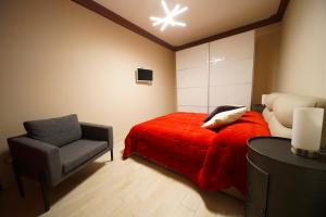 ein Schlafzimmer mit einem roten Bett und einem Stuhl in der Unterkunft APPARTAMENTO DA DAVID 2 in Marta