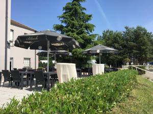 een groep tafels en stoelen met parasols bij Hôtel Restaurant de L'Europort in Saint-Avold