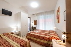 a hotel room with two beds and a television at Hotel Stoccarda in Caorle