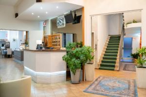 un hall avec des escaliers et des plantes dans un bâtiment dans l'établissement Hotel Stoccarda, à Caorle