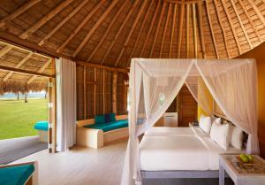 a bedroom in a resort with a bed and a table at Jetwing Surf in Arugam Bay