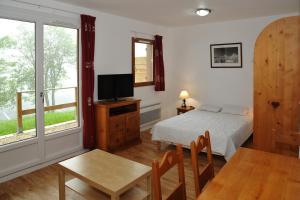 a bedroom with a bed and a table and a tv at Résidence Le Bois de la Reine in Super Besse