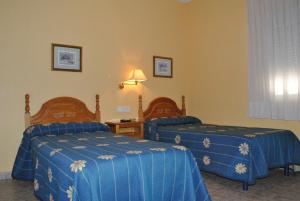 a hotel room with two beds with blue sheets at Hostal Rey Teodomiro in Orihuela