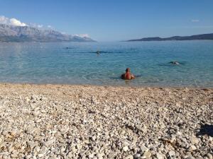 a man in the water on a rocky beach at Villa Sanja in Mimice