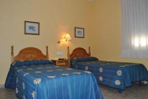 Habitación de hotel con 2 camas con sábanas azules en Hostal Rey Teodomiro, en Orihuela