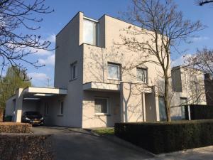 a white house with a car parked in front of it at Bed & Wellness Boxtel, luxe kamer met airco en eigen badkamer in Boxtel