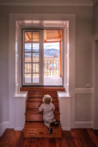 uma criança sentada nas escadas a olhar para fora de uma janela em The Wine Lodges em Funchal