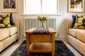 a living room with a table with a vase of flowers on it at Little George, Henley-in-Arden Luxury Apartment with Private Parking in Henley in Arden