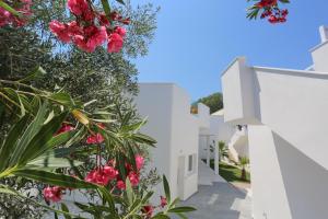 a walkway between white buildings with pink flowers at Lefko Suites in Hanioti