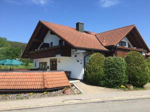 una casa con techo rojo y algunos arbustos en Gästehaus RIESENBÜHL, en Schluchsee