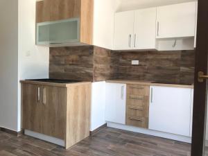 an empty kitchen with white cabinets and wooden floors at Apartments Simoneta in Malinska