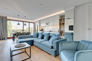 ein Wohnzimmer mit blauen Sofas und eine Küche in der Unterkunft Staywin Riverfront Lofts in Danzig