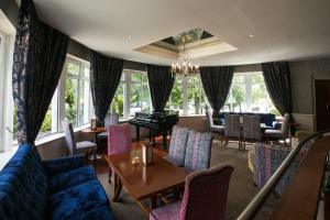 a restaurant with chairs and tables and a blue couch at Fitzgeralds Woodlands House Hotel in Adare