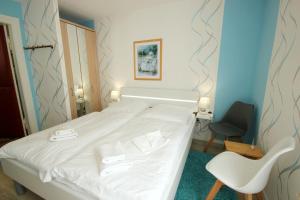 a hotel room with a white bed and a chair at Villa Wilhelmshöhe by Rujana in Binz