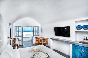 a living room with a table and a television at Diamond Luxury Suites Collection in Oia