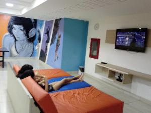 Una donna sdraiata su un letto a guardare la TV di Apt 602 Barra ,climatizado arena jeunese a Rio de Janeiro