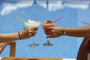 two people holding cocktails in front of a pool at Archontiko Naoumidi in Portaria