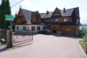 une grande maison en bois avec une voiture garée devant elle dans l'établissement Dom Wczasowy Krystyna, à Bukowina Tatrzańska