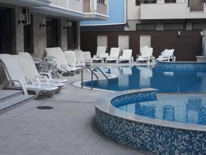 uma piscina com cadeiras brancas e um monte de móveis em Таня 8 em Pomorie