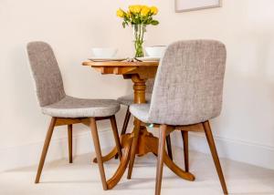 two chairs at a wooden table with a vase of flowers at Little George, Henley-in-Arden Luxury Apartment in Henley in Arden