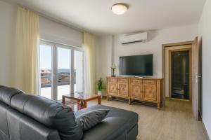 sala de estar con sofá y TV de pantalla plana en Apartments Apollo en Trogir