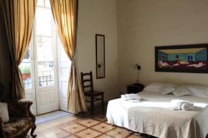 a bedroom with a bed and a chair and a window at Aloi Rooms in Catania