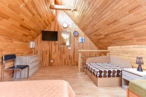 a bedroom with a wooden ceiling with a bed and a tv at Kotedžiukai Šventojoje in Šventoji