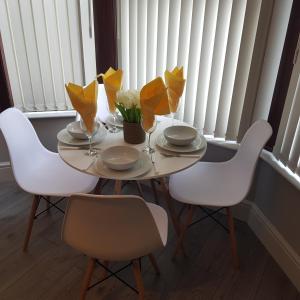 uma mesa com cadeiras brancas e papel de tecido amarelo em Hollis House em Derby