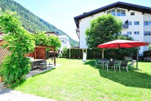 a garden with a table and umbrella and a building at Aparthaus Teresa in Ried im Oberinntal