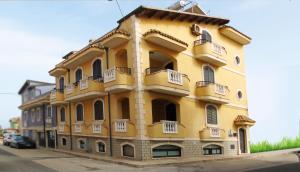 un edificio amarillo con balcones en un lateral en Casa Vacanza All'Estremo Sud en Portopalo