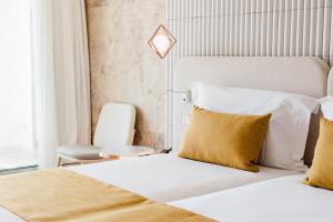 a hotel room with a bed and a chair at Aguas de Ibiza Grand Luxe Hotel - Small Luxury Hotel of the World in Santa Eularia des Riu