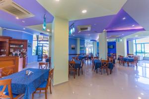 una sala da pranzo con tavoli, sedie e soffitti viola di Hotel Bahamas a Sarandë