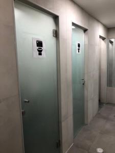 a row of elevators with glass doors in a bathroom at Vistas de Lisboa Hostel in Lisbon