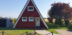 een klein rood huis met een driehoekig dak bij Murmel 3 - Strandkorb, Wallbox, WLan, Kamin in Carolinensiel