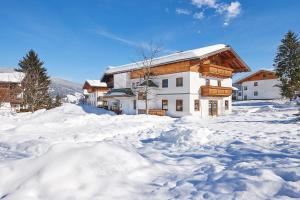 a house in the snow with a pile of snow at Sonnberg Ferienanlage in Flachau