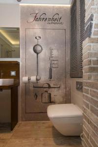 a bathroom with a toilet and a sign on the wall at Patio Apartments - Old Town in Gdańsk