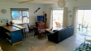sala de estar con sofá, mesa y TV en Blue Space Beach house, en Port Shepstone