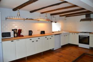 uma grande cozinha com armários brancos e pisos de madeira em Gitesonoro Beho em Gouvy