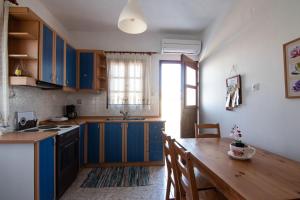 a kitchen with blue cabinets and a wooden table at Athena's Houses in Skiros