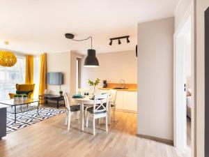 a living room with a dining room table and a kitchen at VacationClub – Rezydencja Park Orła Apartament 12 in Mielno