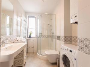 a bathroom with a shower sink and a washing machine at VacationClub – Rezydencja Park Orła Apartament 12 in Mielno