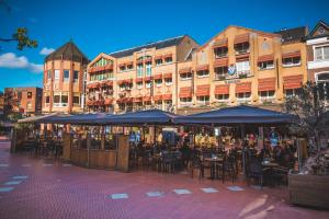 埃因霍温女王酒店的一组桌椅,在建筑前摆放遮阳伞