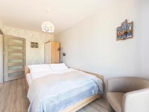 sypialnia z białym łóżkiem i krzesłem w obiekcie VacationClub - Pionierów 6, Apartament 25 w mieście Mielno