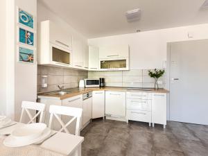 kuchnia z białymi szafkami i białymi urządzeniami w obiekcie VacationClub - Pionierów 6, Apartament 25 w mieście Mielno