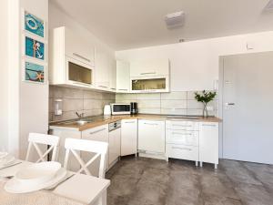 a kitchen with white cabinets and white appliances at VacationClub - Pionierów 6, Apartament 25 in Mielno