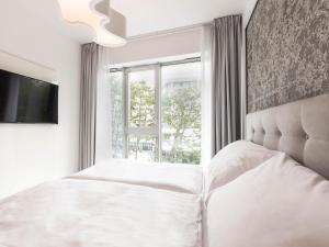 biała sypialnia z łóżkiem i oknem w obiekcie VacationClub – Dune B Apartament 3.23 w mieście Mielno
