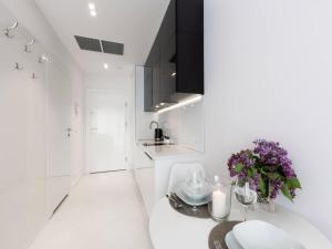 a white kitchen with a table with purple flowers at VacationClub – Dune B Apartament 3.23 in Mielno
