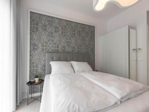 sypialnia z białym łóżkiem i ścianą w obiekcie VacationClub – Dune B Apartament 3.22 w mieście Mielno