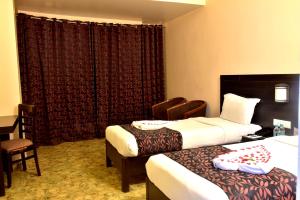 um quarto de hotel com duas camas e uma cadeira em Hotel City Inn em Varanasi