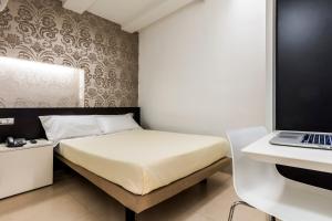 1 dormitorio con cama y escritorio con ordenador portátil en Savoy Hotel, en Parma